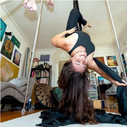 Woman hanging upside down in aerial silk. 