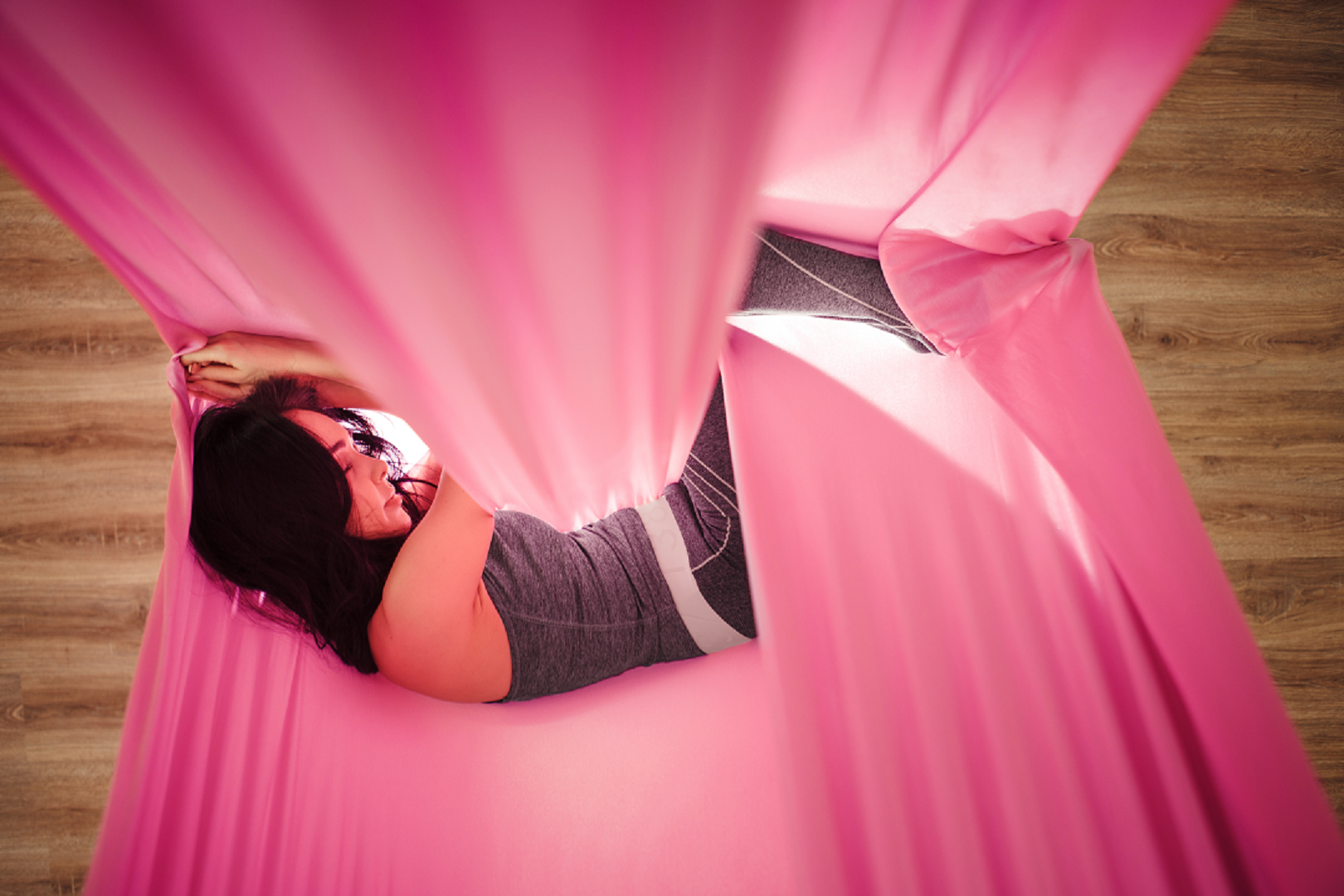 Girl sleeping pr resting on her pink aerial hammock